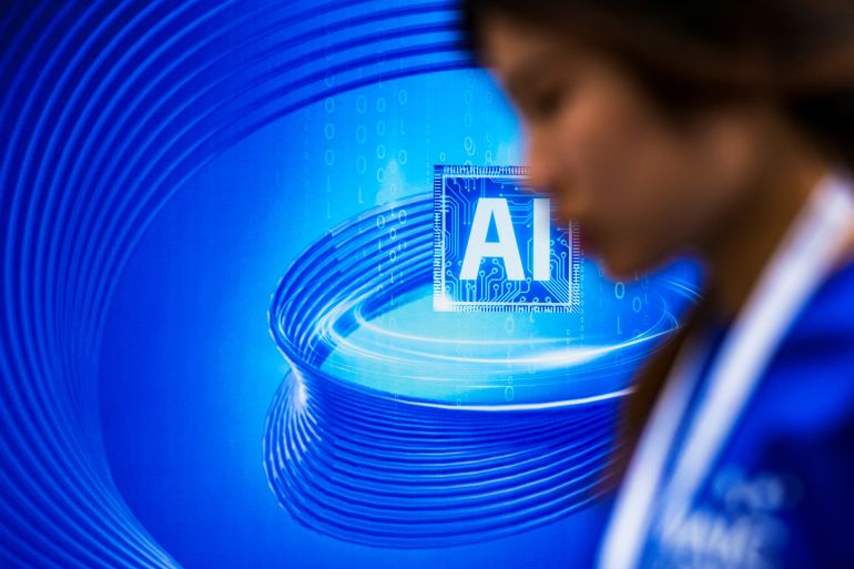 A delegate walks past a blue board reading AI at a conference on artificial intelligence