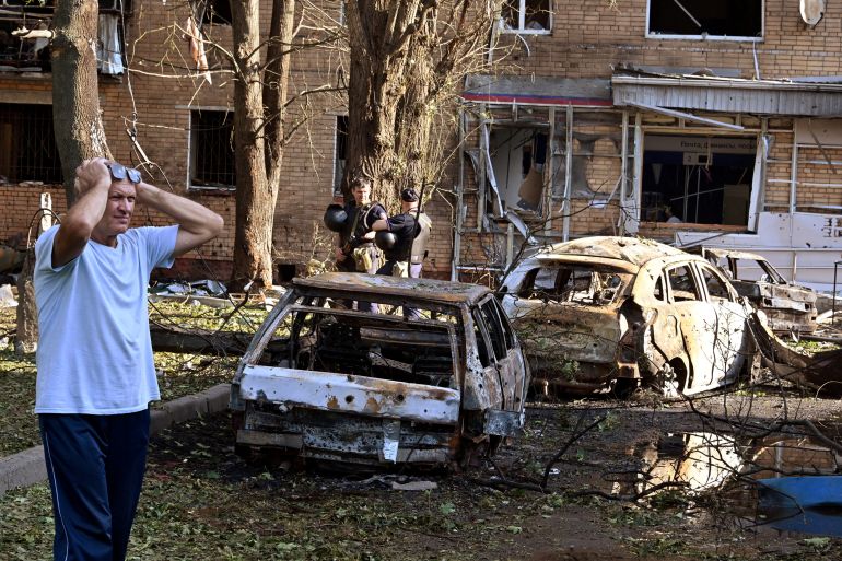 A man reacts while standing next to burnt-out remains of cars in the courtyard of a multi-storey residential building, which according to local authorities was hit by debris from a destroyed Ukrainian missile, in the course of Russia-Ukraine conflict in Kursk, Russia August 11, 2024. Kommersant Photo/Anatoliy Zhdanov via REUTERS RUSSIA OUT. NO COMMERCIAL OR EDITORIAL SALES IN RUSSIA. TPX IMAGES OF THE DAY