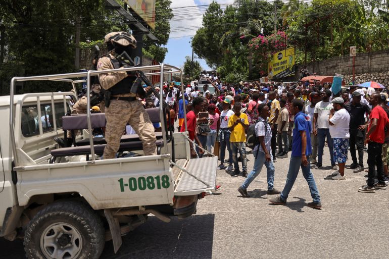 Police officers guard members of the coalition "Du Sang neuf" (New Blood) during a march against gang violence