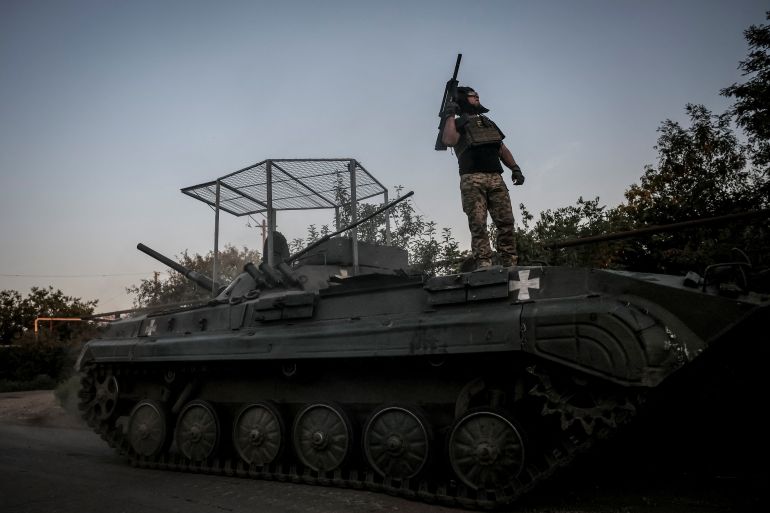 A Ukrainian soldier silhouetted on top of an armoured fighting vehicle