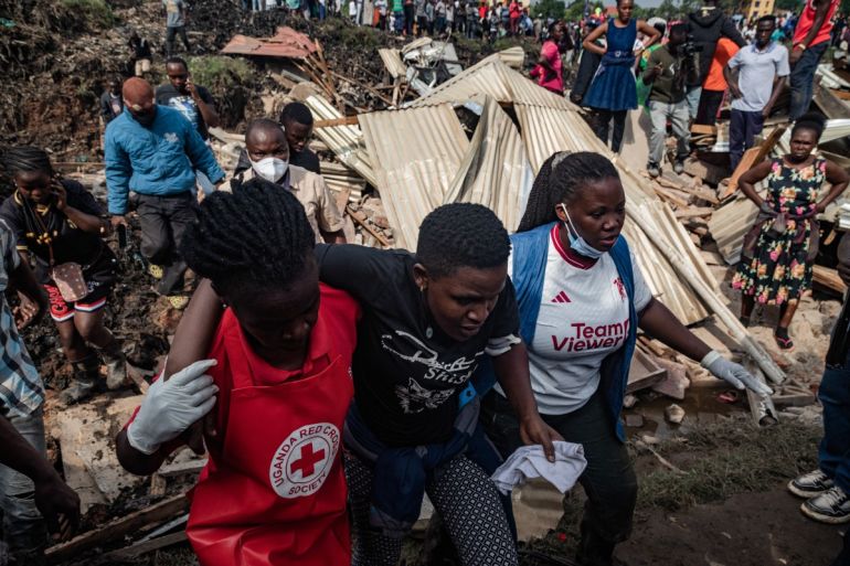 Red Cross officers hold a bereaved family member who lost her daughter and brother when their house was hit by a landfill collapse