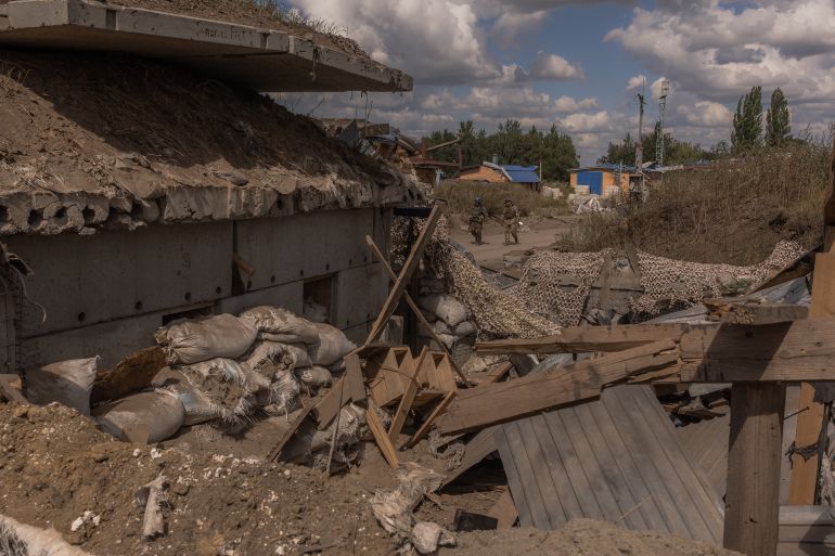 Ukrainian troops at a destroyed Russian border post. The buildings are in ruins.