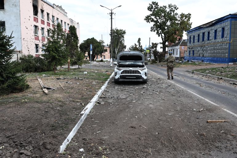 This photograph taken on 16 August, 2024, a media tour organised by Ukraine, shows a Ukrainian soldier walking on a damaged street in Ukrainian-controlled Russian town of Sudzha, Kursk region, amid the Russian invasion in Ukraine. Kyiv said August 16, 2024, its incursion into Russian territory had advanced, claiming it aimed to force Russia to negotiate on "fair" terms, as Moscow's troops announced new gains in eastern Ukraine. Two and a half years into Russia's invasion of Ukraine, Kyiv's troops on August 6, 2024, launched a major counter-offensive into Russia's Kursk region, sending more than 120,000 people fleeing. (Photo by Yan DOBRONOSOV / AFP)