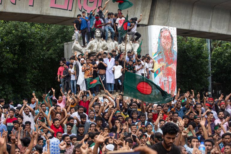 Protesters climb a public monument as they celebrate after getting the news of Prime Minister Sheikh Hasina's resignation, in Dhaka, Bangladesh