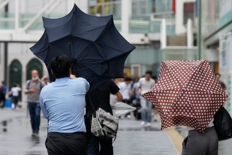 A man in Tokyo struggles against strong wind brought by Typhoon Ampil