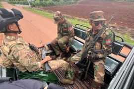 Anti-coup fighters on the back of a pick-up truck. They are in uniform and holding their weapons.