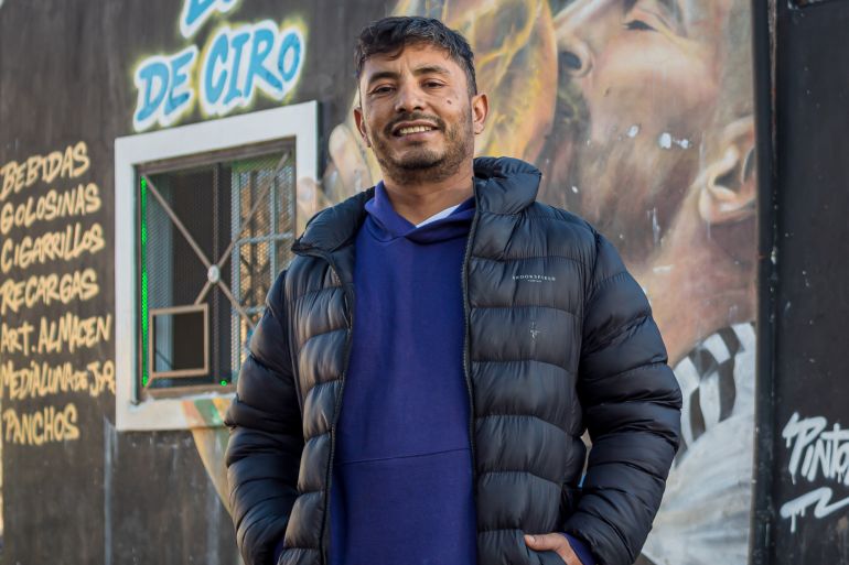 Waldemar Cubilla stands in front of a mural of Lionell Messi kissing the World Cup trophy